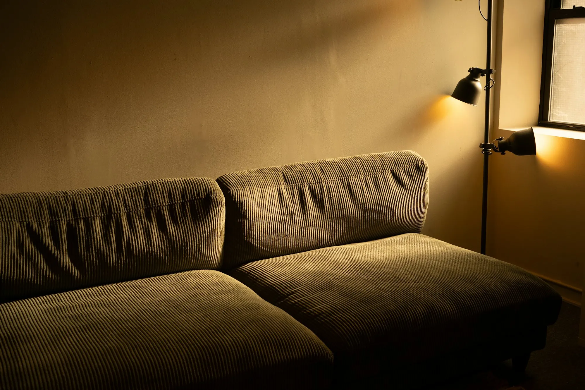 Corduroy sofa lit by a warm wall lamp